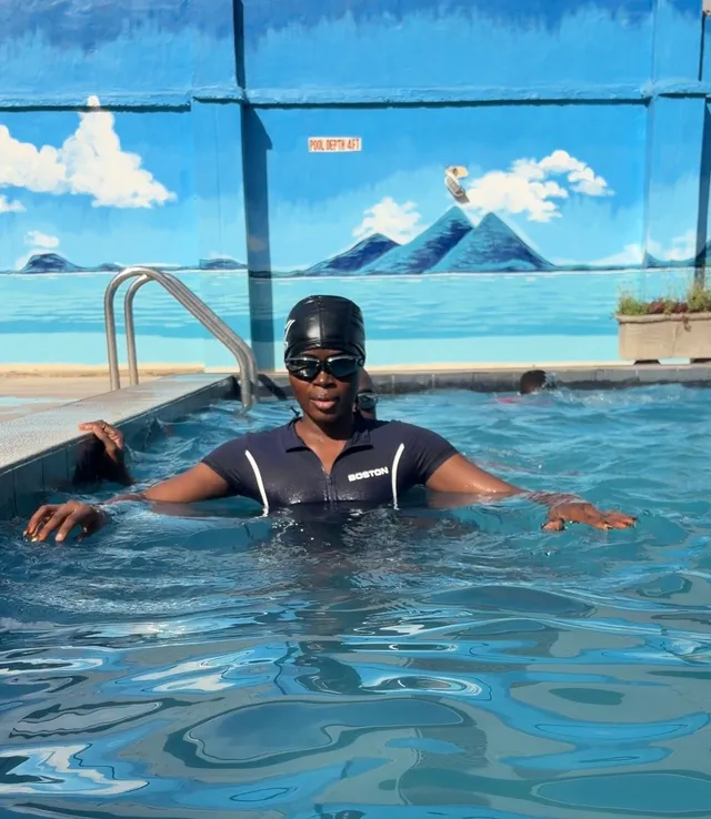 Oyeyinka in a swimming pool, wearing a swim cap and goggles